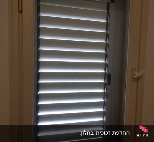 חלון זכוכית עם תריסים סגורים למחצה